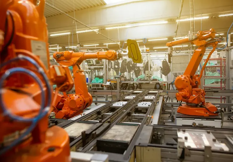 Orange industrial robot arms working along an automated production line
