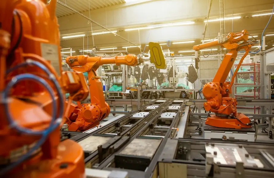Orange industrial robot arms working along an automated production line