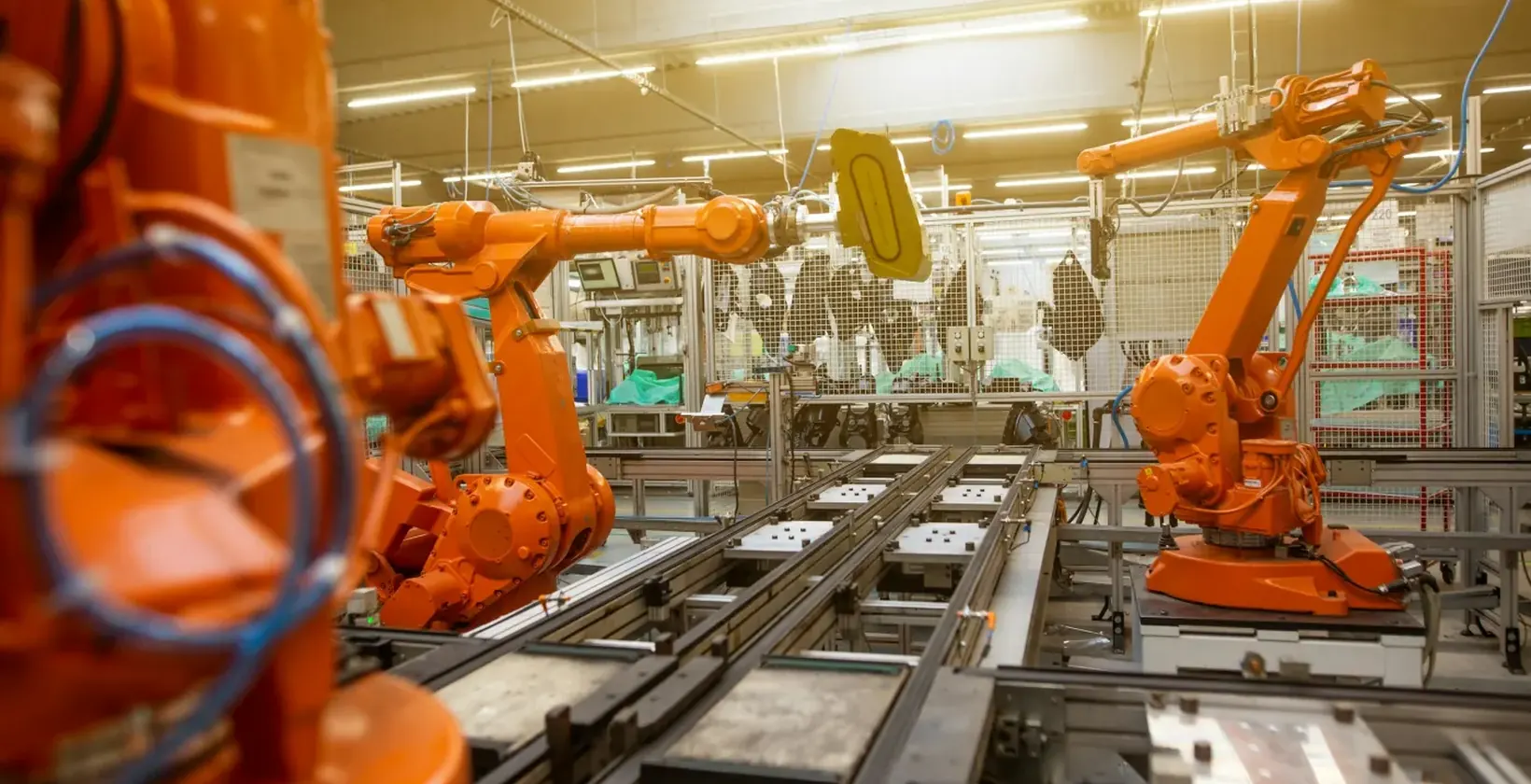 Orange industrial robot arms working along an automated production line