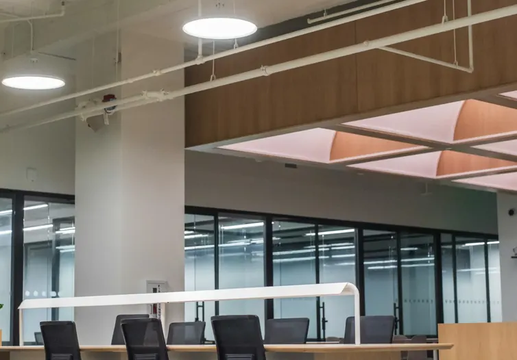 Open-plan office with desks and chairs beside a glass meeting room
