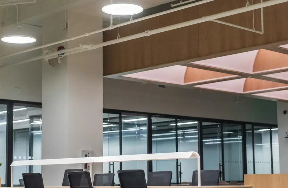 Open-plan office with desks and chairs beside a glass meeting room