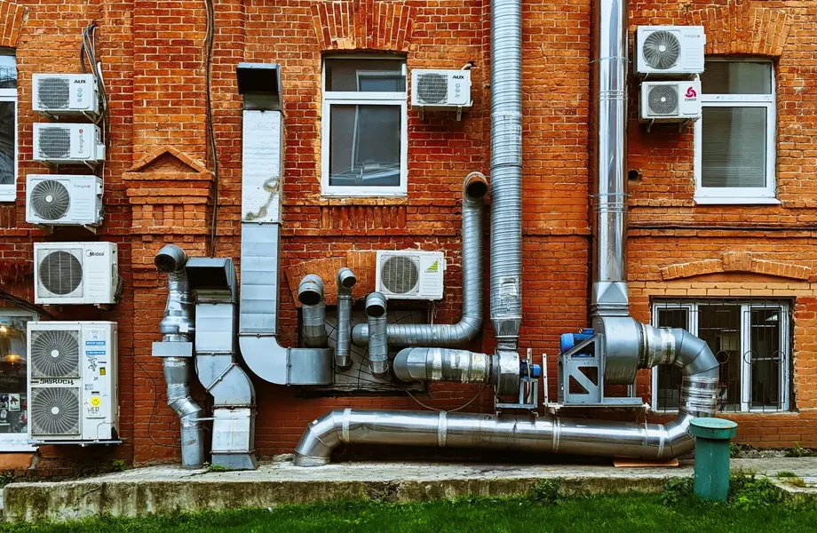 Air conditioning units and ductwork on the outside wall of a brick building