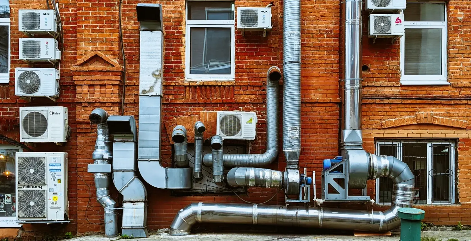 Air conditioning units and ductwork on the outside wall of a brick building