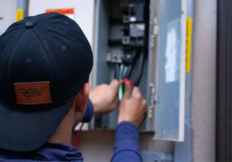 Technician in a cap working on an electrical panel