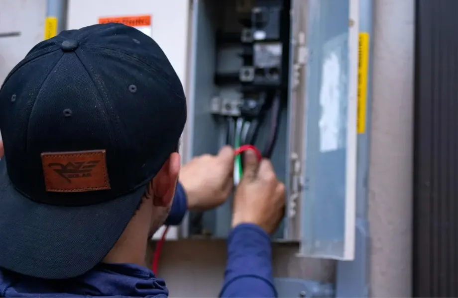 Technician in a cap working on an electrical panel