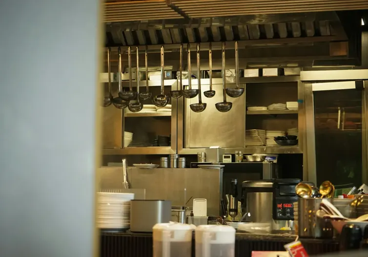 Commercial restaurant kitchen with hanging utensils and steel counters