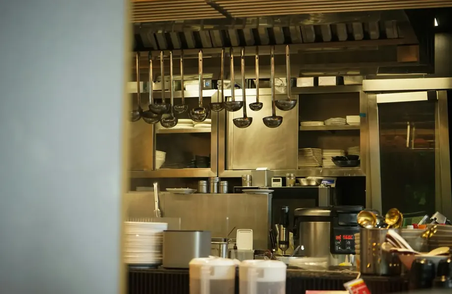 Commercial restaurant kitchen with hanging utensils and steel counters