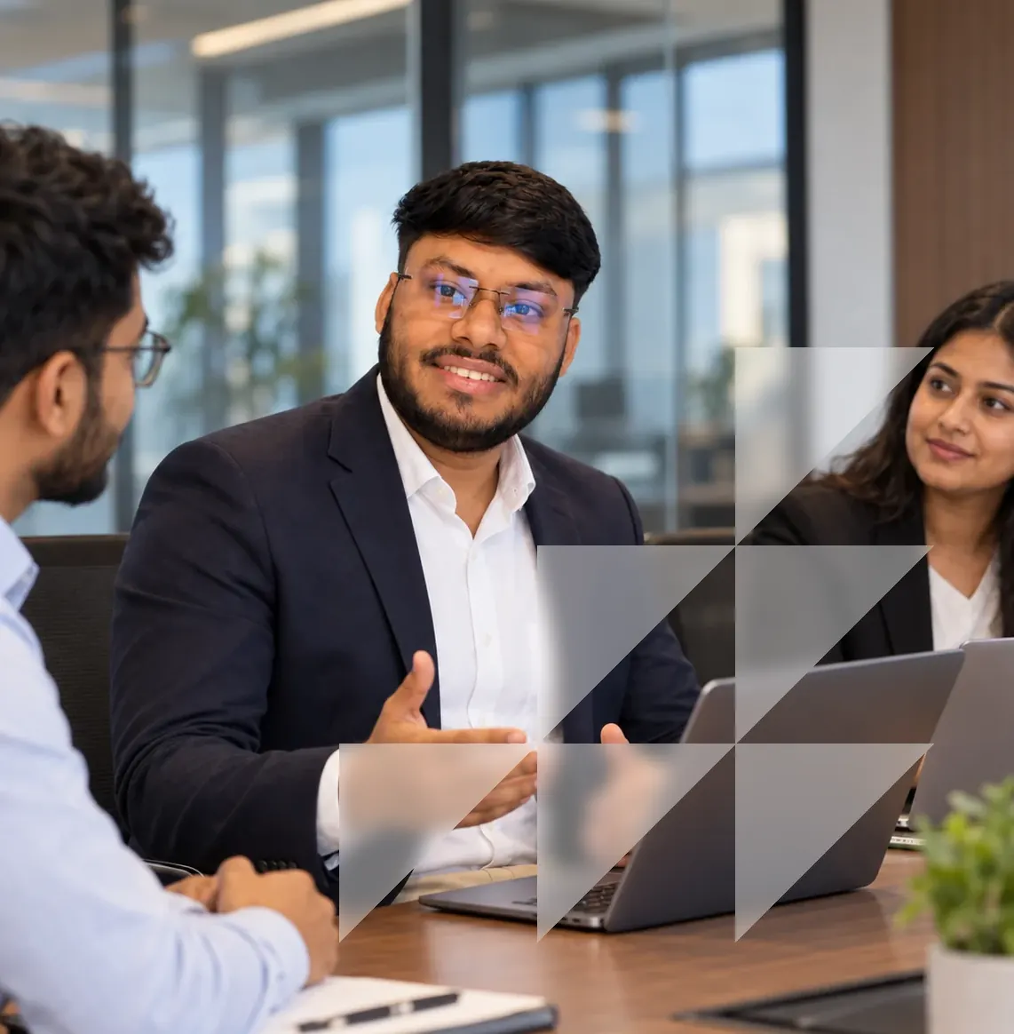 Vikas Saroj in conversation with two people at a meeting table with laptops